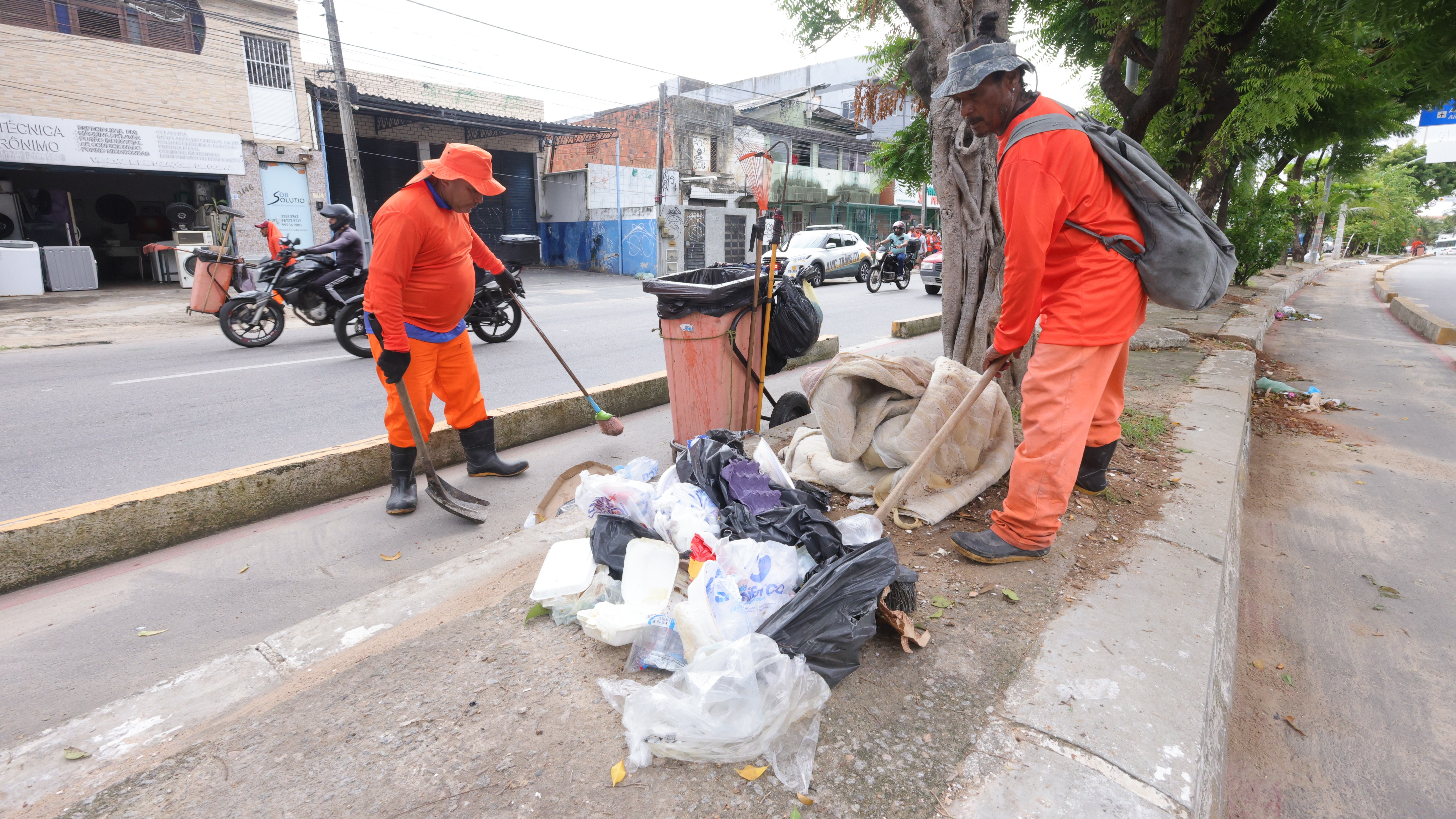 Dois homens recolhendo lixo num canteiro central
